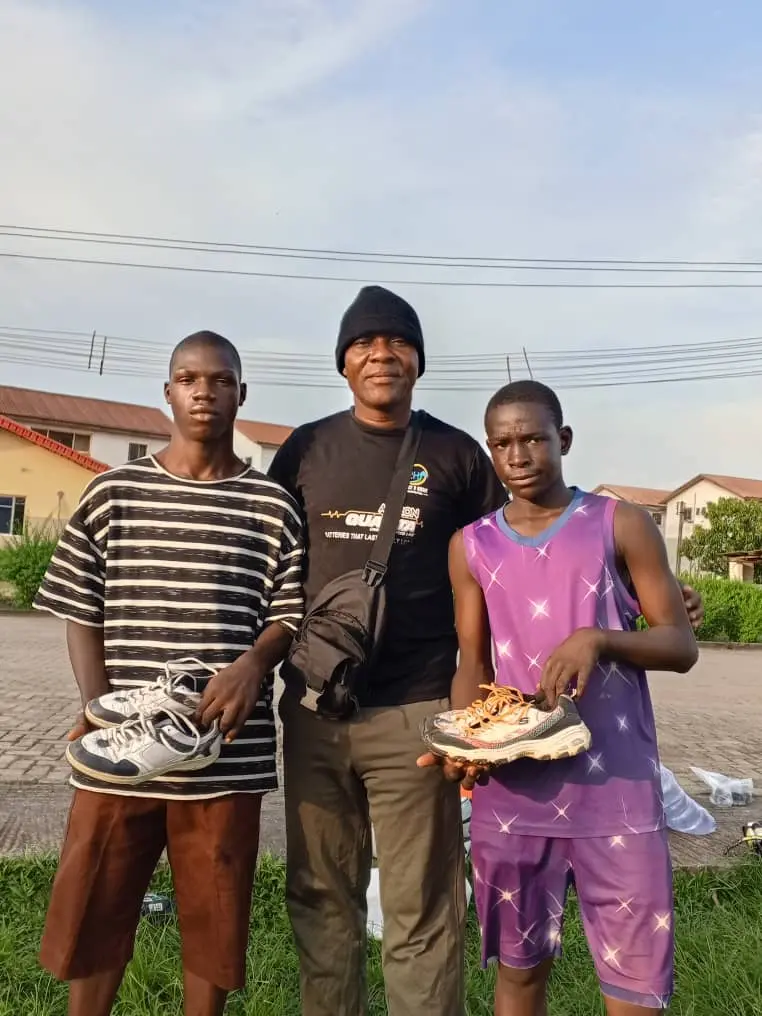 A coach between two young boxers holding up their new training shoes