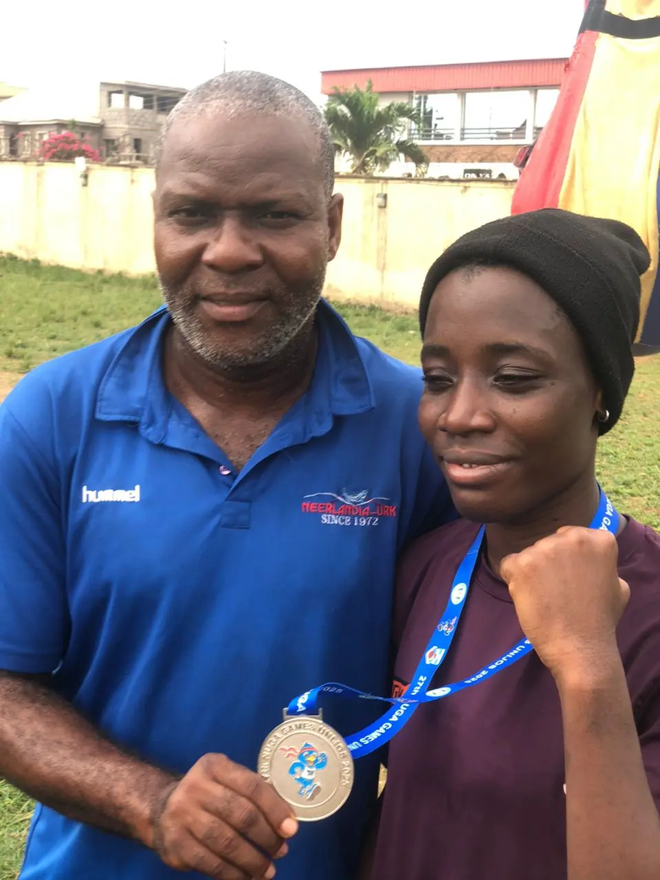 A coach and a young boxer with her medal, fists raised, at training